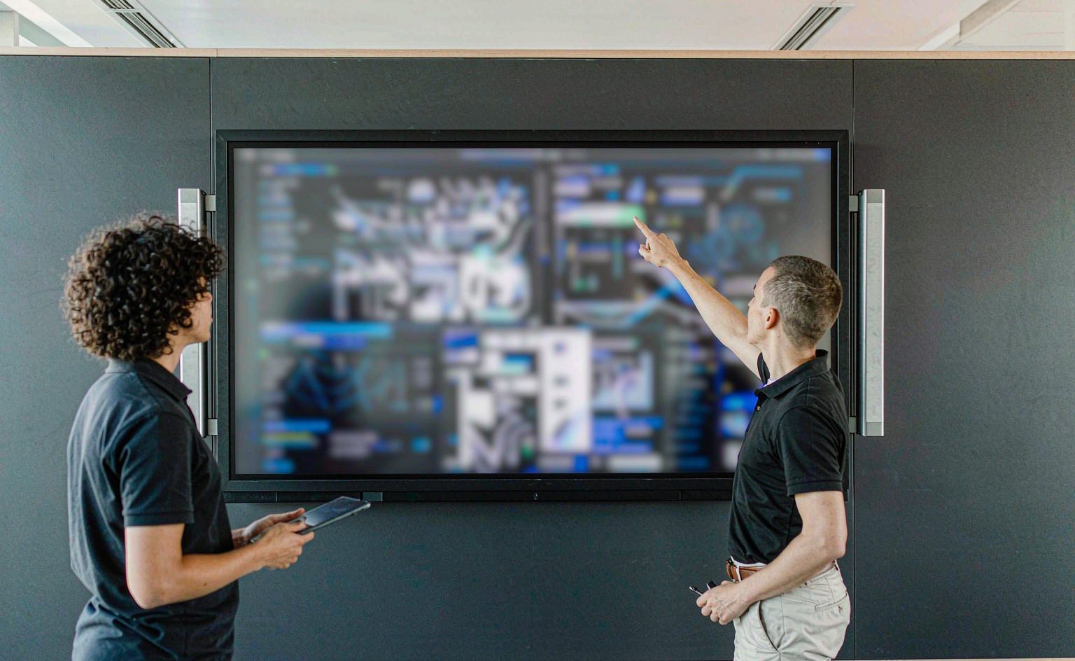 Operations leads reviewing workflow performance charts on a large dashboard screen