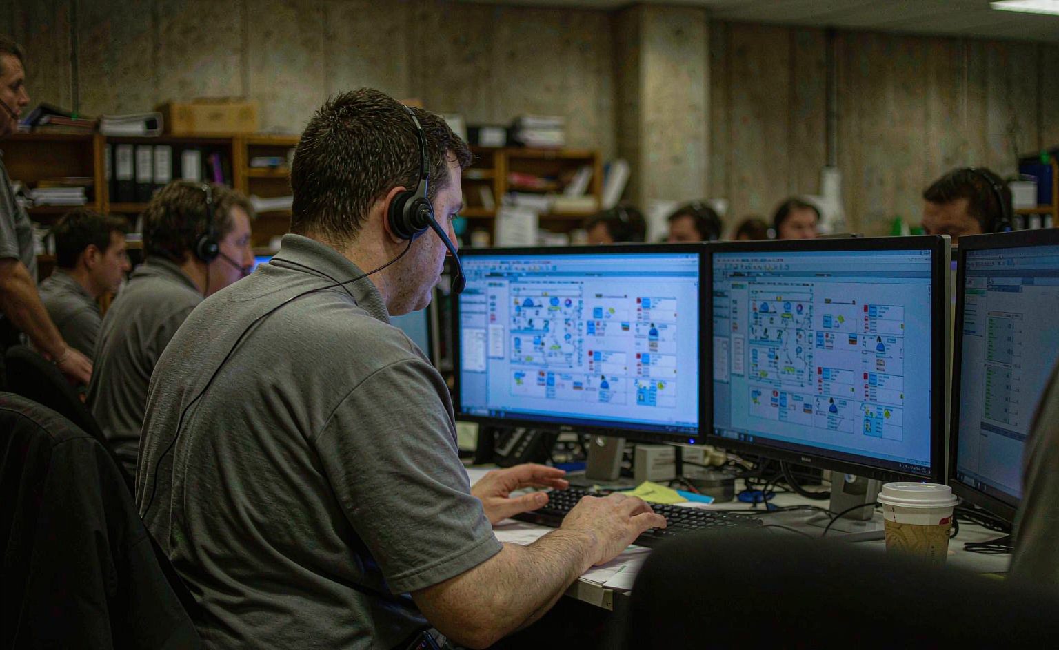 Dispatcher monitoring delivery routes on multiple screens at an operations desk